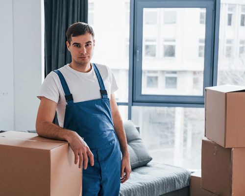 young-male-mover-in-blue-uniform-works-indoors-in-BU9HHGP